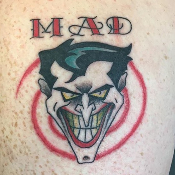 A comic joker face and mad word tattoo