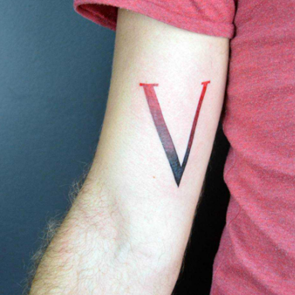 Stunning red and black v-letter tattoo on the hand