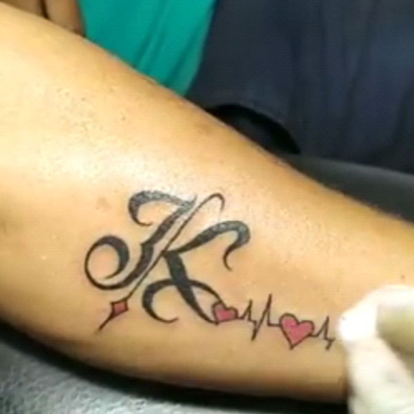 Black k-letter and heartbeat design tattoo